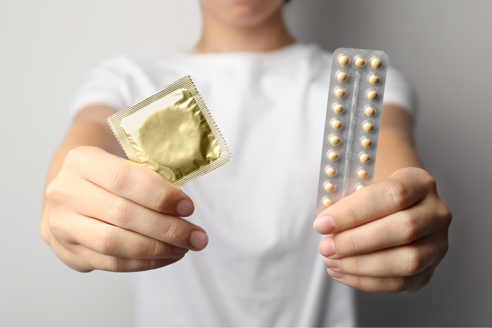 Person holding birth control pills and condoms