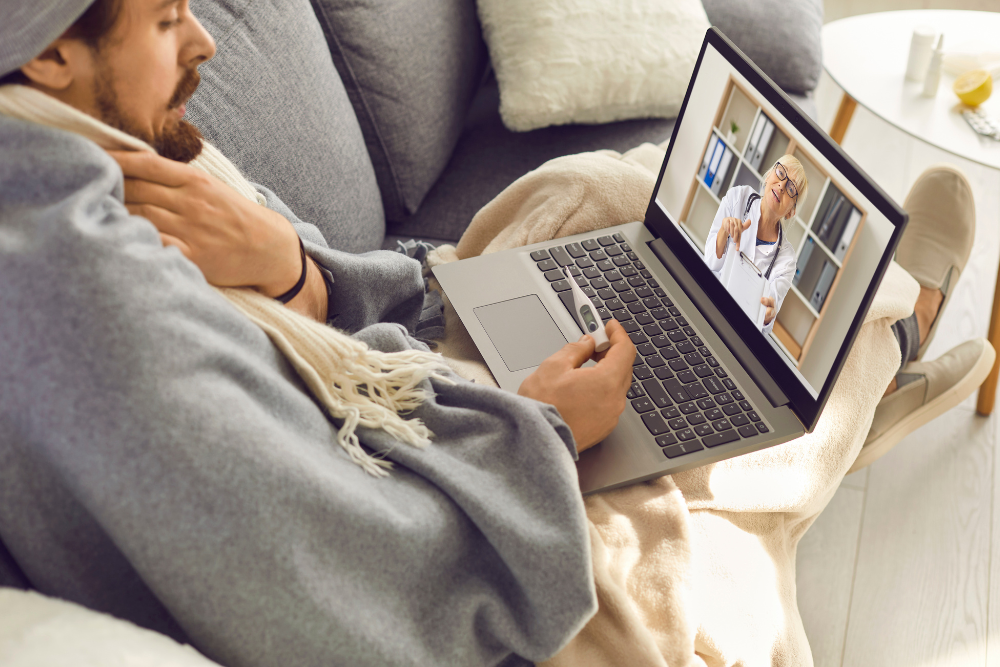 man sick on couch, speaking with online doctor